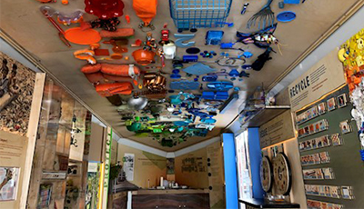 The mobile trash lab with informational displays and trash attached to the ceiling in a rainbow design